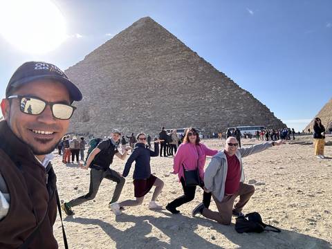       Group of tourists at the Great Pyramid with bright sun.
  