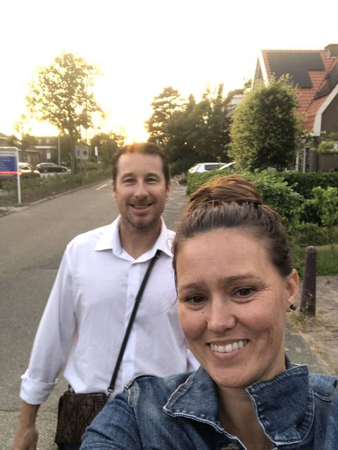 Couple smiling with trees and sunset in the background.