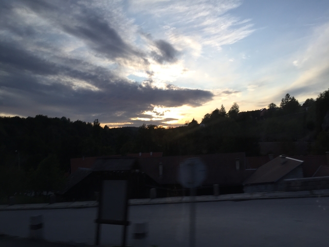       Sunset view with distant hills and some foreground objects, image is blurry.
  