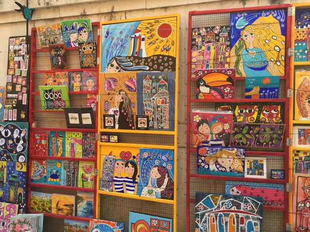       Colorful art display with various vibrant paintings.
  