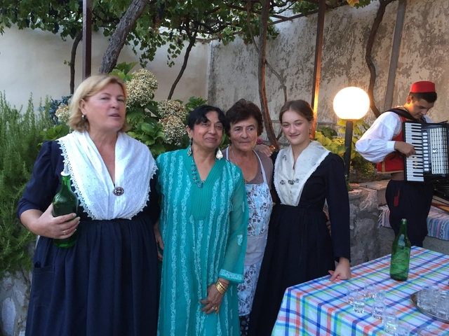       Small group standing next to an accordion player, outdoor setting.
  
