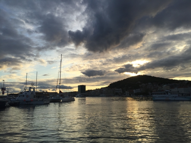       Scenic view of a harbor with boats and dramatic clouds at sunset.
  