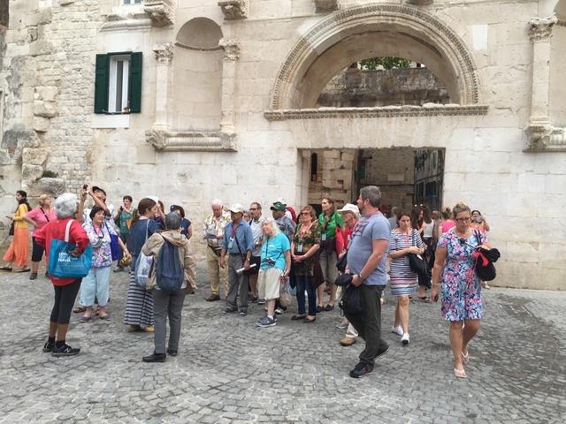       Tourists gathered outside a historic stone gateway.
  