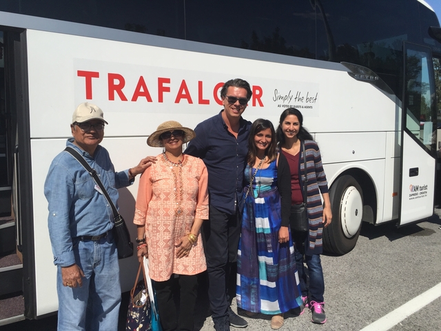       Group posing in front of a white bus with 'Trafalgar' branding.
  