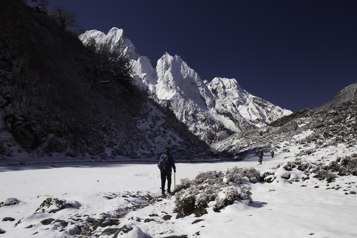 Hikers walking through a snow-covered mountain valley.
