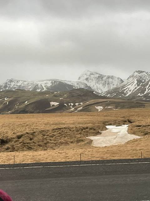       Mountain road with snowy peaks in the background.
  