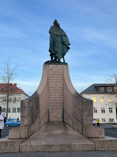       Statue of a historical figure with buildings in the background.
  