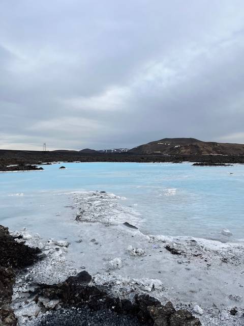       A scenic view of a geothermal lagoon surrounded by rocky terrain.
  