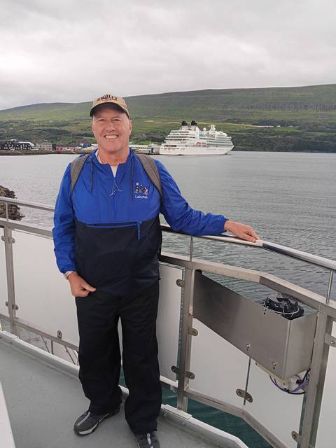       A person on a boat with a cruise ship in the background.
  