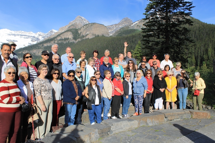 Large group of tourists posing with mountains in the background.