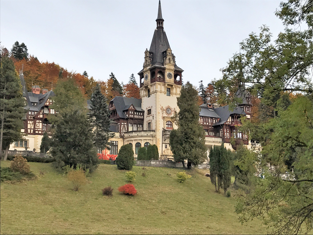 A grand historic building set in a lush green landscape.