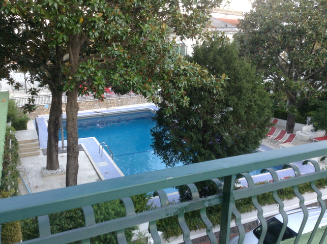 A pool surrounded by trees and a residential building.