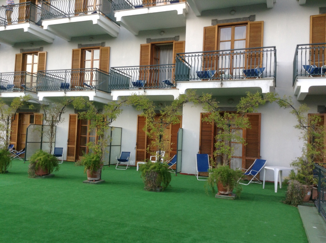 A building with balconies and greenery on the ground.