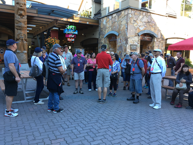 Group of tourists listening to a guide in a plaza.