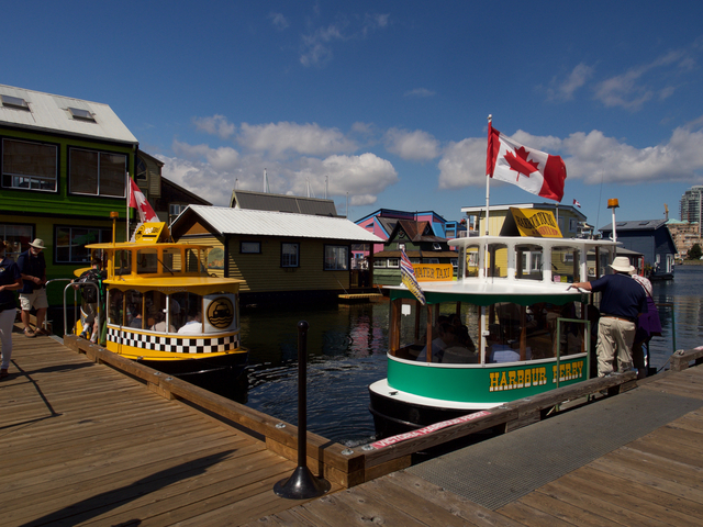 Harbour ferries with Canadian flag docked at a pier.