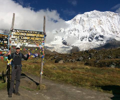       Hiker at Annapurna Base Camp with welcoming signs.
  