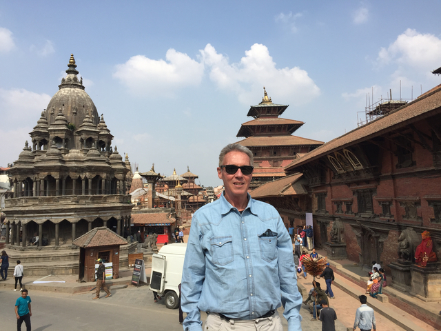 Man posing in front of historic buildings and temples.