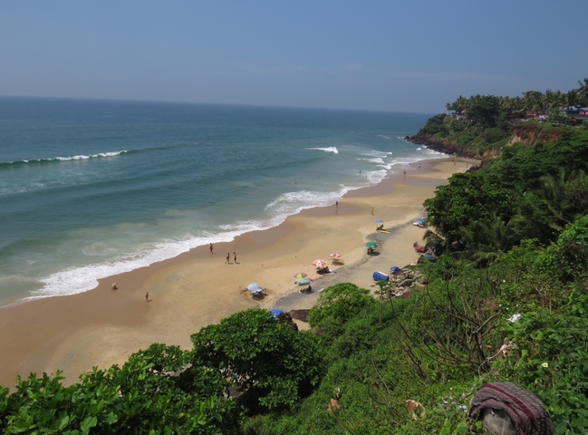       Sandy beach with colorful umbrellas and lush greenery.
  