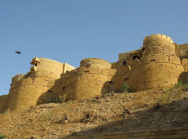       Large fort with sandstone walls under a clear sky.
  