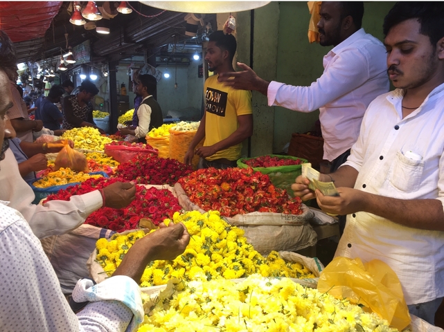 People buying and selling flowers in a busy market.