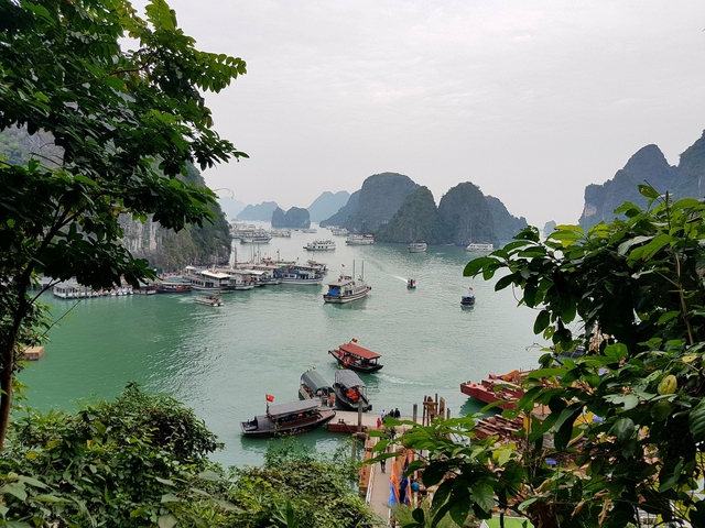 Harbor view of boats and limestone formations with greenery.