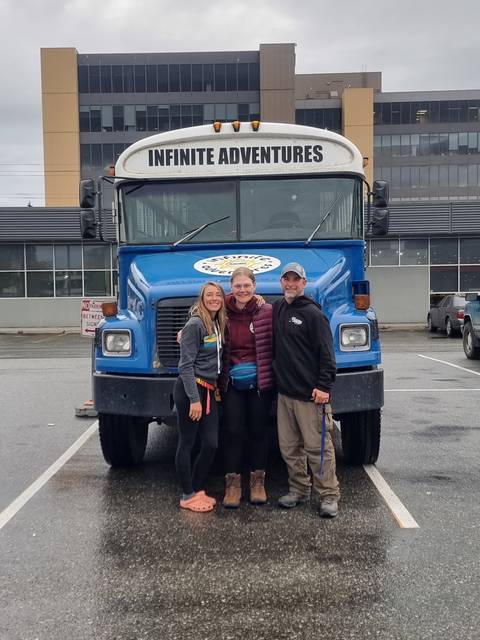       Group of people standing in front of a tour bus.
  