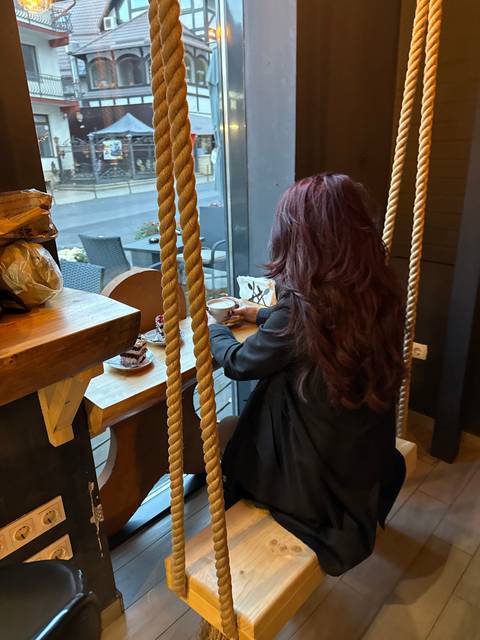 Woman sitting by a window in a café with ropes.