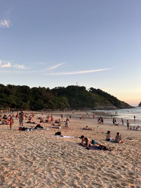 Crowded beach scene with people relaxing on the sand.