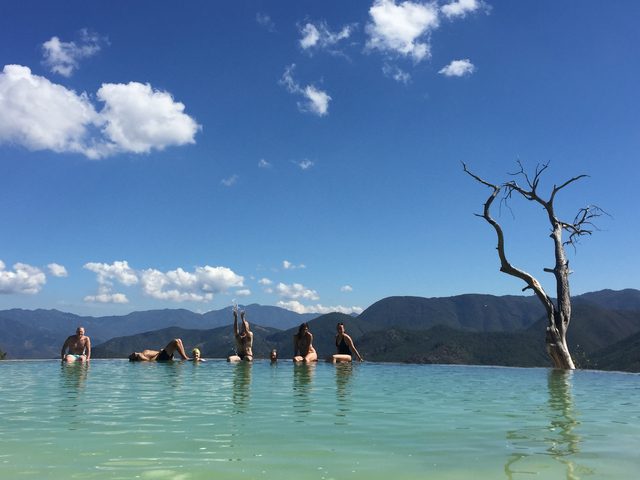 People relaxing in a pool with mountains in the background.