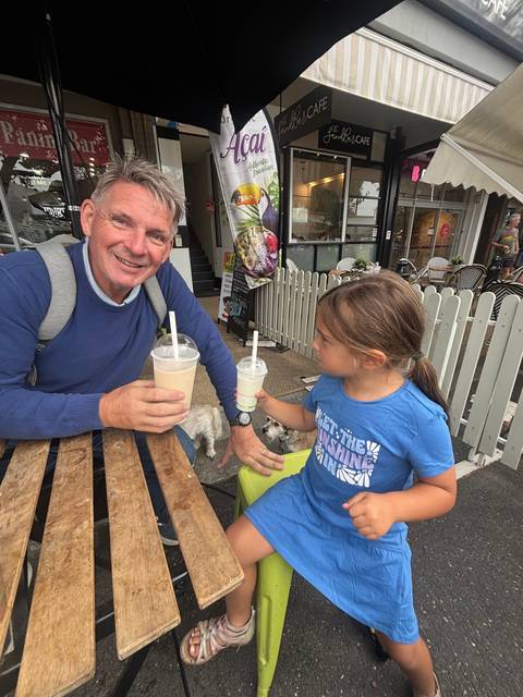 A man and a child having drinks outside a cafe.