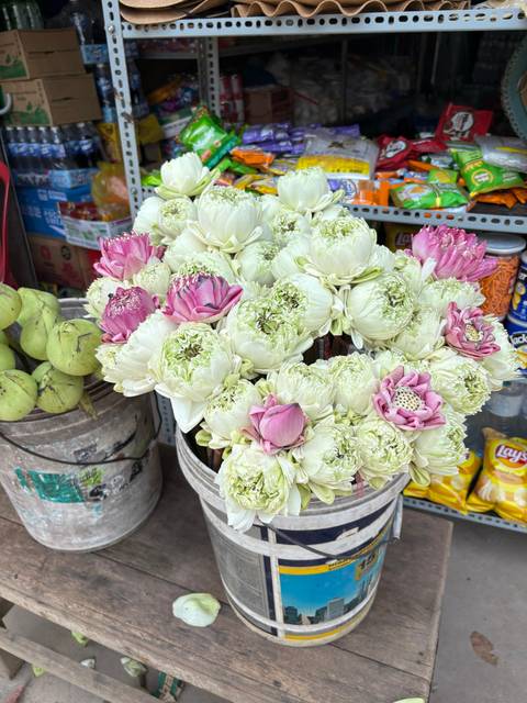       Bouquets of pink and white lotus flowers in a market setting.
  