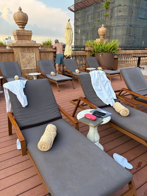       Lounge chairs and people on a deck area with rolled towels.
  