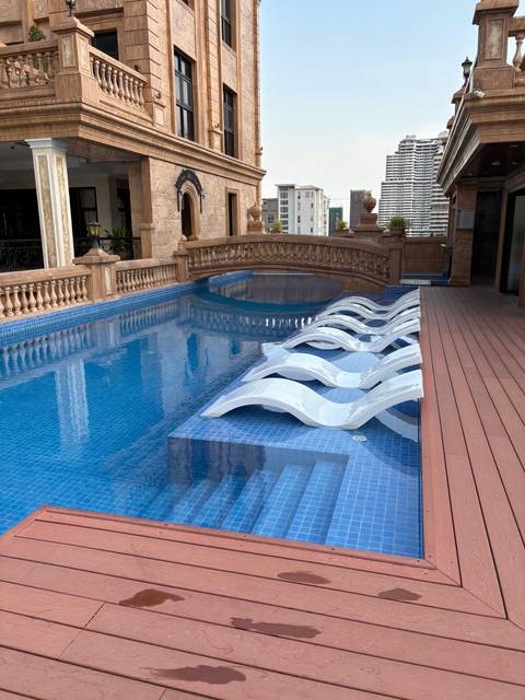      A rooftop swimming pool with loungers and city skyline.
  