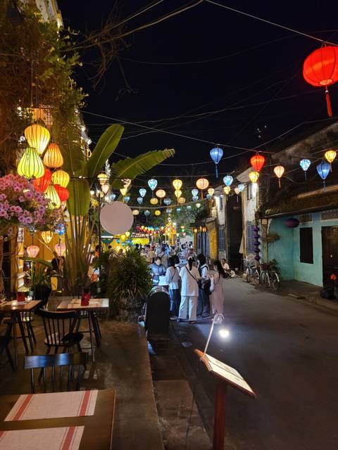 Vibrant street scene at night with colorful lanterns and people walking.