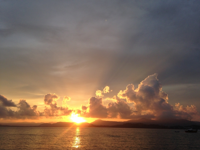 Dramatic sunset with clouds and mountain silhouette.