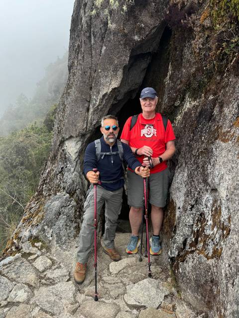 Two people between rocks, carrying hiking poles.