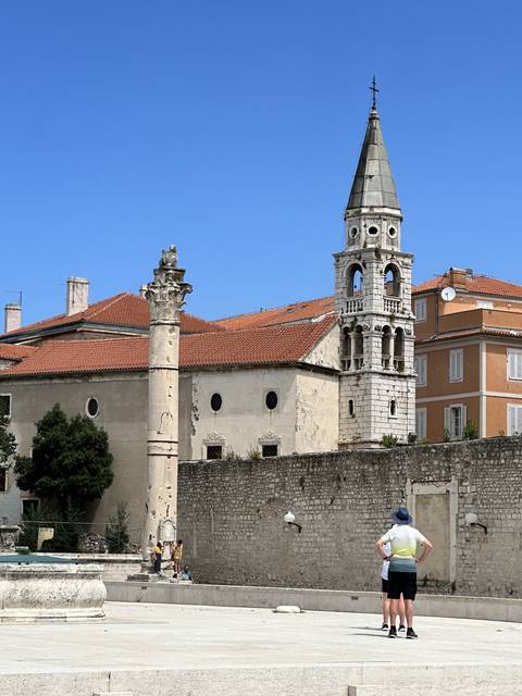 Historic building with a tall tower and tourists.