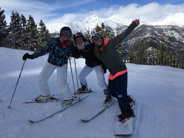 Three people posing with skis on a snowy mountain.