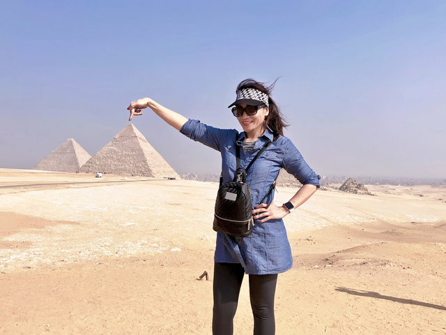       Woman pointing to the pyramids in the Giza desert.
  