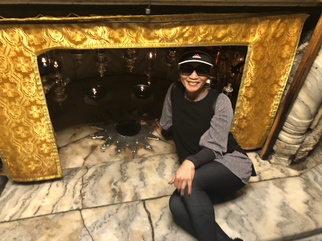       Woman posing at a holy site with candles.
  
