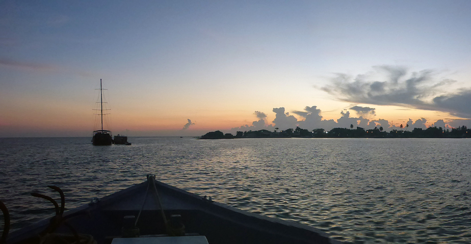 Silhouette of boats at sunset on the ocean.