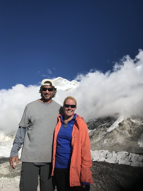 Two people posing in front of a mountain peak covered in clouds.