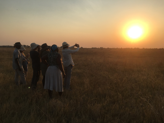      People enjoying a sunset on a safari.
  