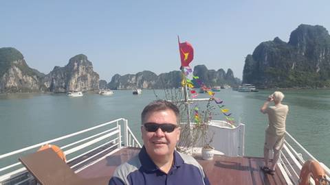       Person on the deck of a boat with scenic cliffs in the background.
  