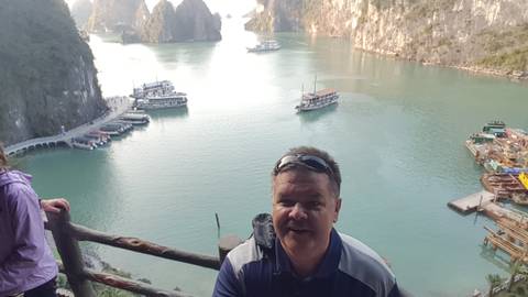       A person standing at a viewpoint overlooking a scenic bay.
  