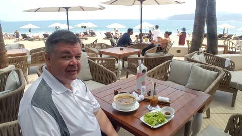       Person dining at a beachside restaurant with a seafood dish.
  