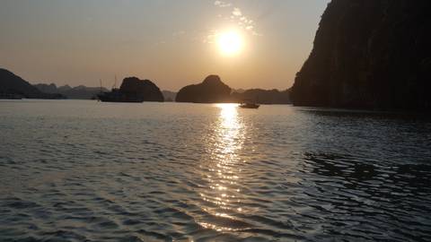       Boat in the distance on a bay with limestone formations at sunset.
  