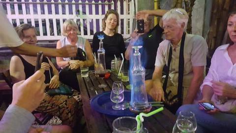       Group of people sitting at a table with drinks and glasses.
  
