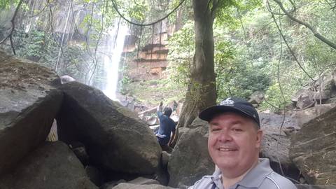       Person sitting among rocks with a waterfall in the background.
  
