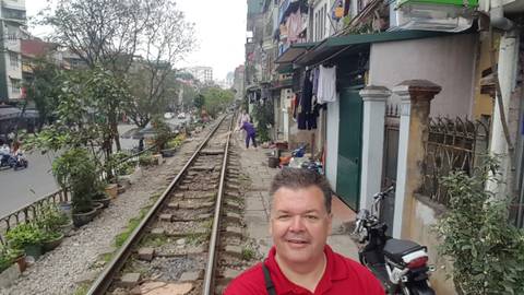       Person standing beside a railway track with a street in the background.
  
